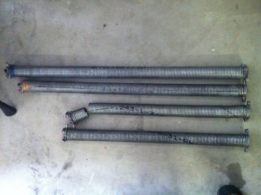 A pair of galvanized torsion springs next to a pair of high cycle galvanized torsion springs